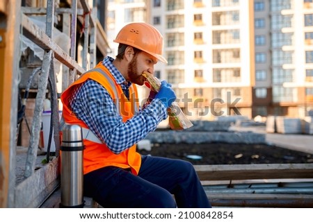 Construction worker eating sandwich during lunch break Royalty-Free Stock Photo #2100842854