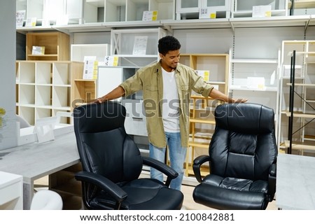 Man choosing office armchairs in furniture store Royalty-Free Stock Photo #2100842881
