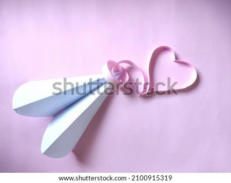 paper airplane and heart shaped paper tape on colored background. Valentine's Day image.