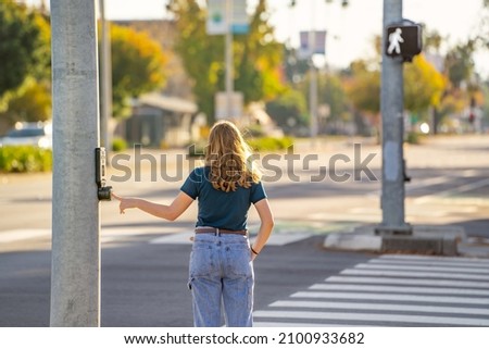 A young woman pressing the button to cross the road. 