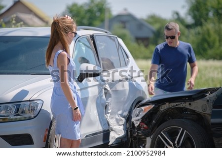 Angry woman and man drivers of heavily damaged vehicles arguing who is guilty in car crash accident on street side. Road safety and insurance concept Royalty-Free Stock Photo #2100952984