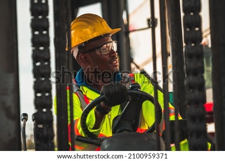 African american man driving forklift in shipyard . Logistics supply chain management and international goods export concept . Royalty-Free Stock Photo #2100959371