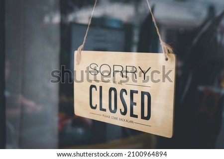 Blurred picture of a sign hanging behind the shop glass window that says "Sorry we are closed". Business service and food drink concept.