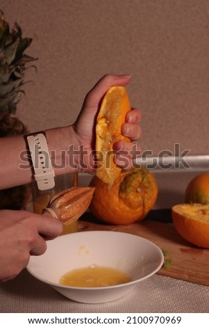 Hand squeezes a cut orange
