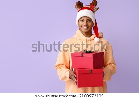 African-American man with Christmas gifts on color background