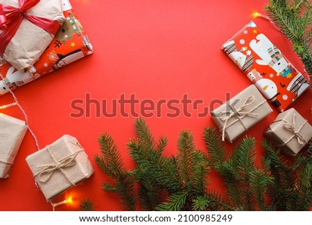 Christmas composition with gift boxes, clews of rope, paper's rools and decorations, fir tree branches on red background. Preparation for holidays. Top view with copy space, flat lay, layout, flatly.