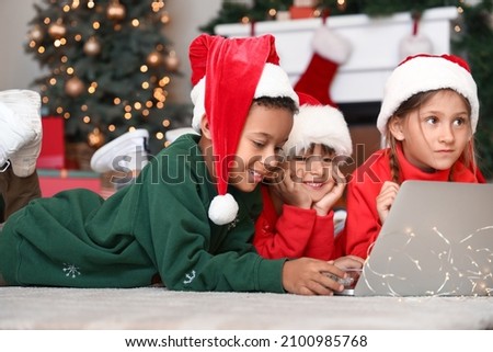 Cute little children with laptop watching cartoons at home on Christmas eve