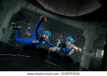 A man and a woman enjoy flying together in a wind tunnel. Free fall simulator Royalty-Free Stock Photo #2100995836