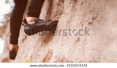 A person climbs the mountain in special climbing shoes, close-up view of the legs with copy space. A woman is engaged in active extreme sports, mountaineering and climbing. Royalty-Free Stock Photo #2101014334
