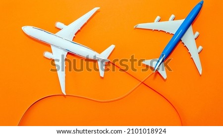 Two passenger aircraft in flight on a beautiful orange background top view, aircraft flying with a contrail, copy space. Airline travel concept