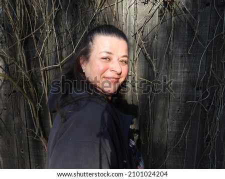 smiling woman stand in front of a wooden hut in the mountains of Austria