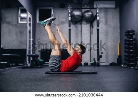 Fitness routine and weight loss, sports life. Man correctly performs demanding core exercises on the pathos of the modern gym and sports center concept. Individual training and achieving fitness goals Royalty-Free Stock Photo #2101030444