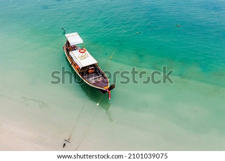 Aerial view of a Long Tail boat floating and anchored on a shallow water by the beach