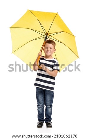 Cute little boy with open yellow umbrella on white background
