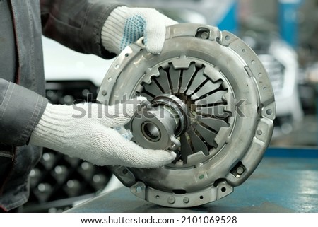 Auto parts. Clutch kit close-up. An auto mechanic checks the technical condition of the drive disc, the driven disc and the exhaust bearing. Repair and maintenance in a car service. Royalty-Free Stock Photo #2101069528
