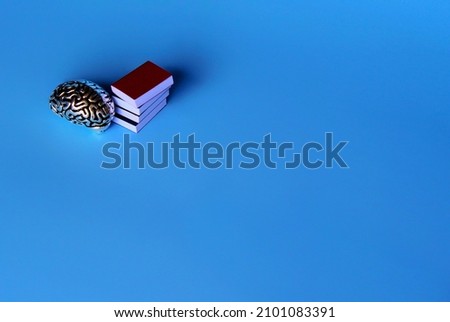 Education and knowledge concept. Brain model and pile of books on blue background with copy space.