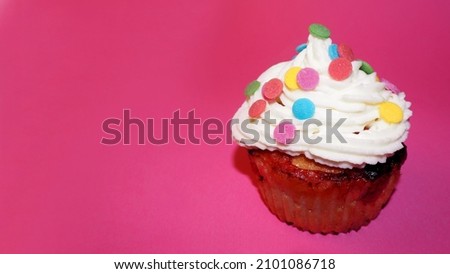 yogurt muffin with red currants, smeared with white cream of cream and mascarpone, decorated with multicolored round splashes on a pink background. side view. Birthday. copy space