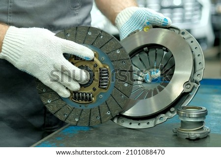 Car spare parts. The clutch kit is in the hands of an auto mechanic. Monitoring of the technical condition of the drive disc, the driven disc and the exhaust bearing. Repair and maintenance in a car s Royalty-Free Stock Photo #2101088470