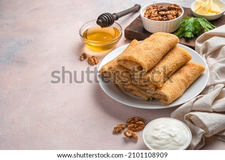 Stuffed homemade pancakes on a light background with sour cream, honey and nuts. Top view, copy space. Mardi Gras.