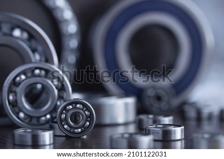 Set of deep groove ball and roller bearings on a gray background with soft focus. Axial chrome plated round bearings for heavy equipment and mechanical engineering close-up. Royalty-Free Stock Photo #2101122031