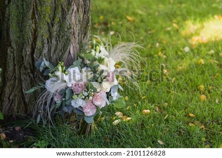 Modern bridal bouquet made from roses, freesia, eustoma and eucalyptus on grass.