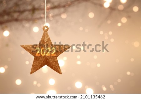 2022 on Christmas star with blurred light background. Happy New Year 2022