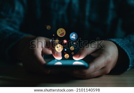 Young man using smartphone sending emojis, diverse positive emoji coming out of mobile phone. Mobile application for chatting, creative image, Social media concept. Royalty-Free Stock Photo #2101140598