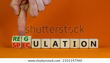 Speculation or regulation symbol. Businessman turns wooden cubes, changes the word speculation to regulation. Beautiful orange background, copy space. Business, speculation or regulation concept. Royalty-Free Stock Photo #2101147960