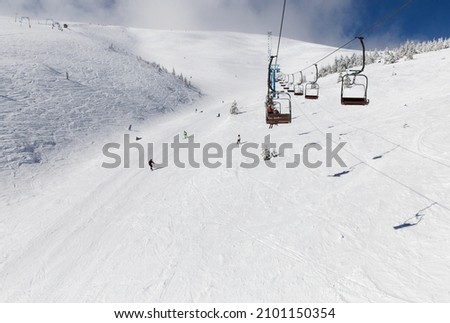 snow ski trail from the height of the lift. Winter season, ski resort, cold sunny snowy weather. Unrecognizable skiers descending the slope of a ski resort Royalty-Free Stock Photo #2101150354
