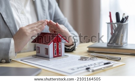 Selling a house with insurance, Salesperson or head of sales uses their hands to protect their model home as a symbol with buy a home get free insurance, Real estate or after sales service.