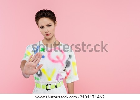 frustrated woman showing stop sign while looking at camera isolated on pink