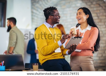 Happy business colleagues using digital tablet while standing in a lobby. Royalty-Free Stock Photo #2101176931