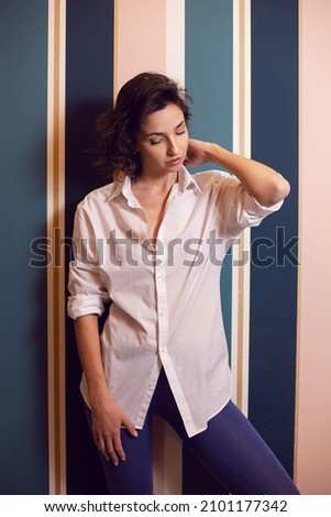cleaning woman in a white shirt stands against a striped wall