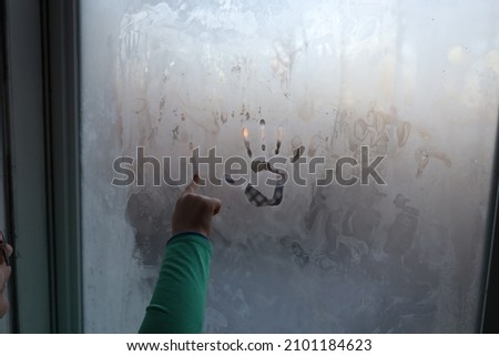 A Child Drawing in the Frost on A Window