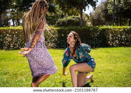 Two women of different ethnicities performing a dance in a garden