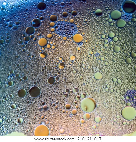 Blue and yellow oil bubbles on water, abstract background