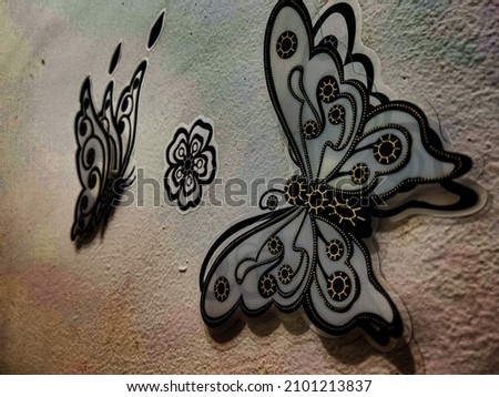 A wall sticker with a picture of two butterflies and a small flower between the two butterflies