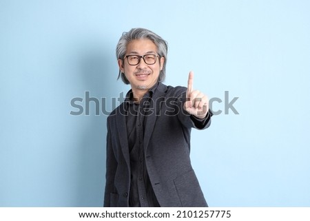 The senior Asian businessman standing on the blue background.