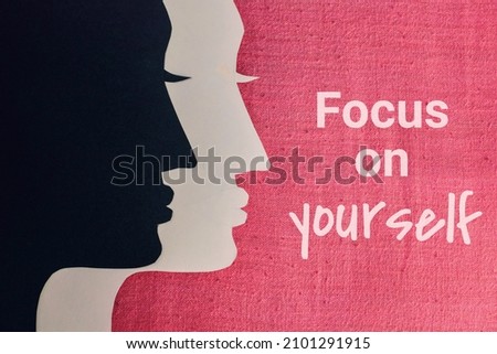 Focus on yourself inscription on fabric background with women face paper art. Top view. 