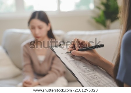 Psychology, depression. Sad, suffering asian young woman consulting with psychologist, psychiatrist while patient counseling mental with doctor woman taking notes at clinic. Encouraging, therapy. Royalty-Free Stock Photo #2101295323