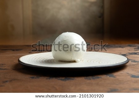 A ball of mozzarella cheese on a wooden table. Selective focus. Royalty-Free Stock Photo #2101301920