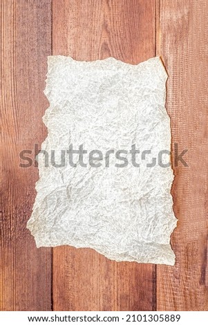 An old blank sheet of parchment paper on a wooden surface. Vertical background, flat lay, copy space, mockup. High quality photo