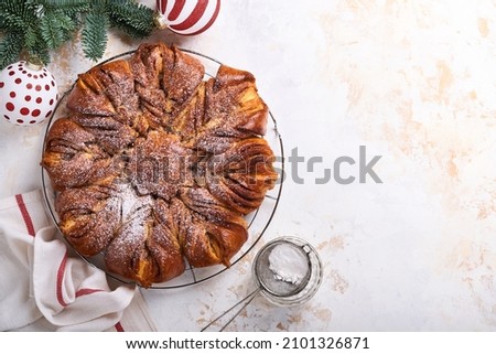 Christmas star braided chocolate and cinnamon bread on white wooden table. Copy space for text. Top view
