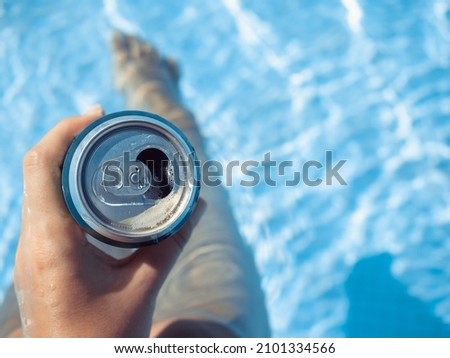 Can of beer and a cute woman on the background of the swim pool. Top view, close-up. Vacation and travel concept. Moments of celebration Royalty-Free Stock Photo #2101334566