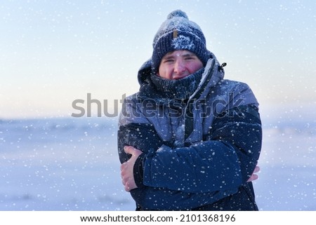 Portrait of frozen suffering guy, young handsome freezing man standing walking outdoors at winter snowy cold frosty day, shaking, trembling, shivering because of extreme low temperature in jacket, hat Royalty-Free Stock Photo #2101368196