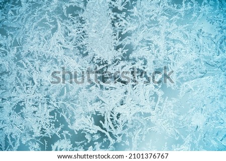 The texture is frozen glass, the background of the frost pattern is blue. Snowflakes on the glass Royalty-Free Stock Photo #2101376767