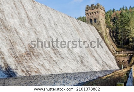 Water overflowing Derwent Dam in Derbyshire UK into Ladybower reservoir Royalty-Free Stock Photo #2101378882