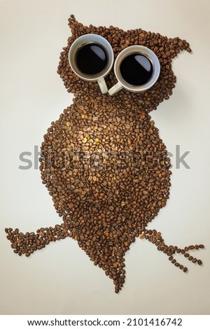 Picture of an owl made of coffee beans and pair cups of coffee