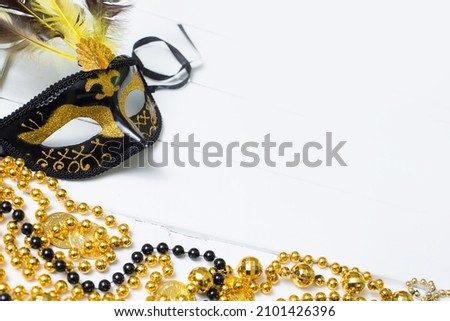 Black and gold Mardi Gras mask and beads on a white background