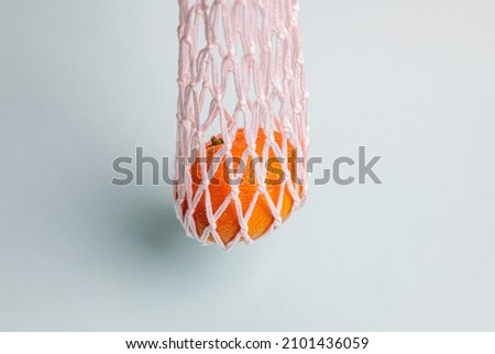 Eco-friendly mesh with tangerines on a blue background. New Year's celebration.